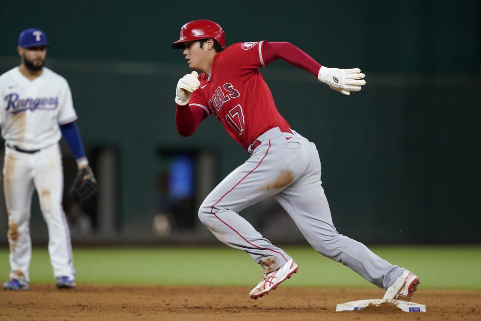 Los Angeles Angels' Shohei Ohtani sprints to third after stealing second as Texas Rangers' Isiah Kiner-Falefa, rear, looks on in the sixth inning of a baseball game in Arlington, Texas, Wednesday, Sept. 29, 2021. Ohtani advanced to third on a throwing error by Rangers catcher Jose Trevino on the play. (AP Photo/Tony Gutierrez)