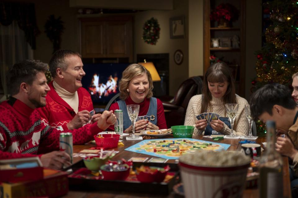 robbie amell, michael hitchcock, kathryn greenwood, and leighton meester sit round a table playing a board game at christmas in exmas movie