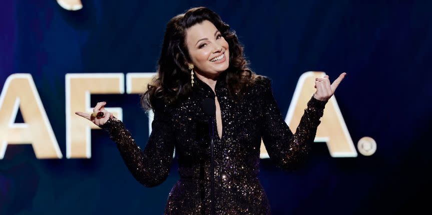 fran drescher smiling and gesturing with both of her index fingers while speaking at a microphone