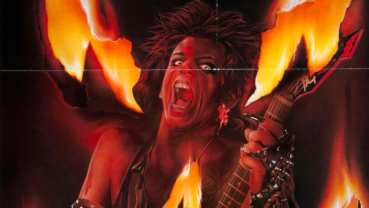  A demonic figure holds a guitar in front of a fiery background 