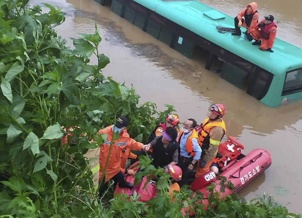 Rescue workers evacuate passengers on a boat from a submerged bus due to heavy rain in Paju, South Korea, Thursday, Aug. 6, 2020. Korean Meteorological Administration issued a warning of heavy rain for Seoul and central area. (Paju Fire Station via AP).