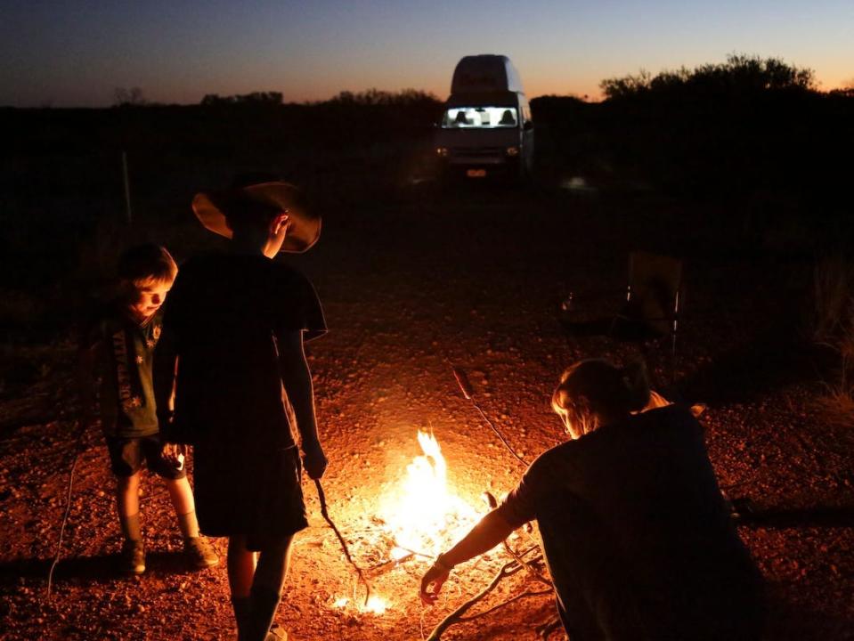 A family gathered around a fire while camping.