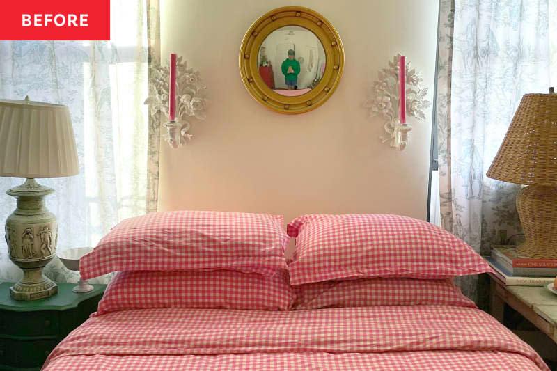 Candle sconces and mirror hang on wall above bed with red gingham bedding flanked by two lamps.