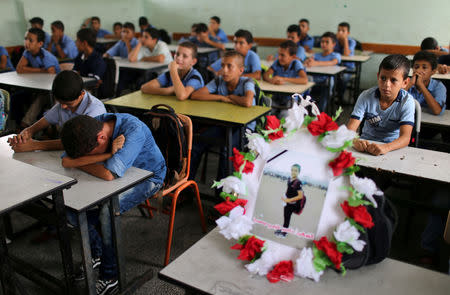 A picture of 12-year-old Palestinian boy Nassir al-Mosabeh, who was killed during a protest at the Israel-Gaza border fence, is seen on his table as his classmates react at a school, in Khan Younis in the southern Gaza Strip September 30, 2018. REUTERS/Ibraheem Abu Mustafa