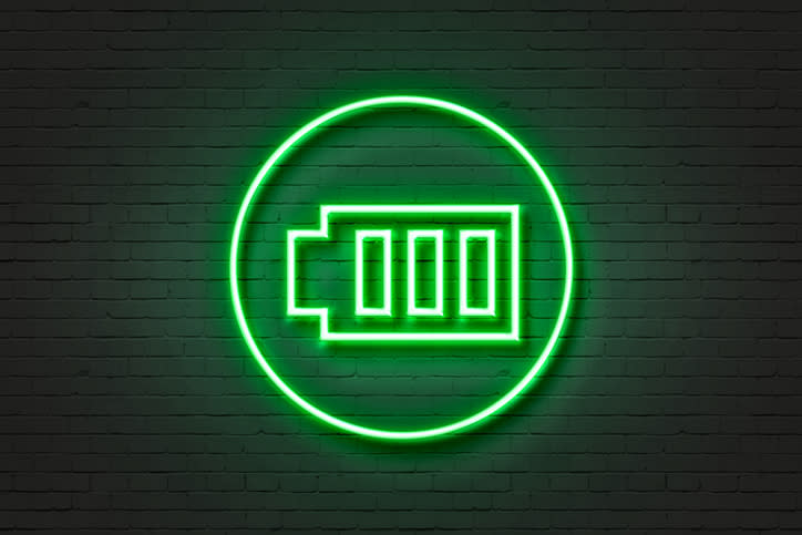 A green neon sign in the shape of a battery.