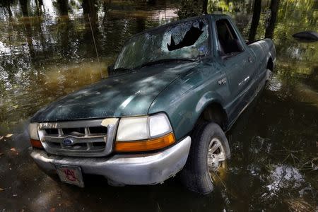 A damaged car is seen in flood waters in St. Amant, Louisiana. REUTERS/Jonathan Bachman
