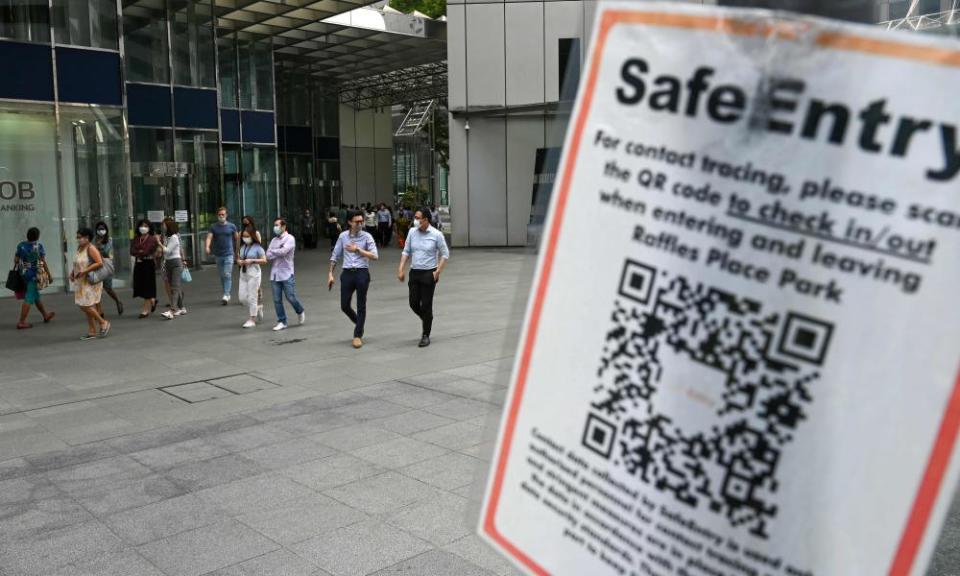 A Covid-19 coronavirus contact tracing sign is pictured as people walk out during lunch break at the Raffles Place financial business district in Singapore on Tuesday.
