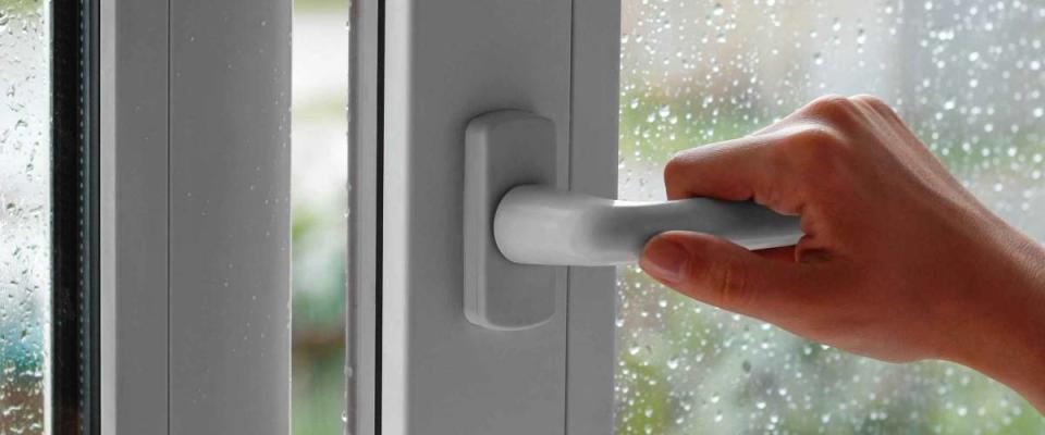 A female hand opens a window with water drops. Closes the window. In the rainy weather. Closeup.