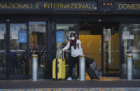 A woman walks upon arrival at the Malpensa airport of Milan, Italy, Sunday, March 22, 2020. For most people, the new coronavirus causes only mild or moderate symptoms. For some it can cause more severe illness, especially in older adults and people with existing health problems. (AP Photo/Antonio Calanni)