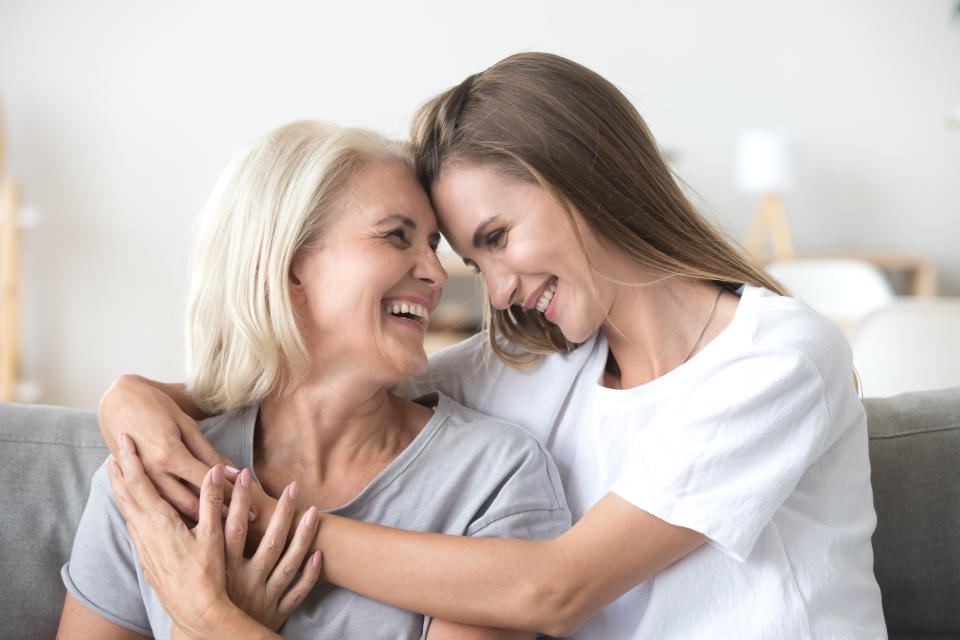 Happy loving older mature mother and grown millennial daughter laughing embracing, caring smiling young woman embracing happy senior middle aged mom having fun at home spending time together