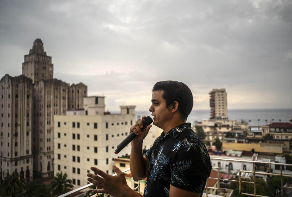 El tenor cubano Andrés Sánchez Joglar serena a sus vecinos desde el balcón de su apartamento en La Habana el domingo 31 de mayo de 2020. El cantante de ópera está dando conciertos desde su casa todos los domingos por la tarde para animar a sus vecinos en cuarentena por la pandemia del coronavirus. (AP Foto/Ramón Espinosa)