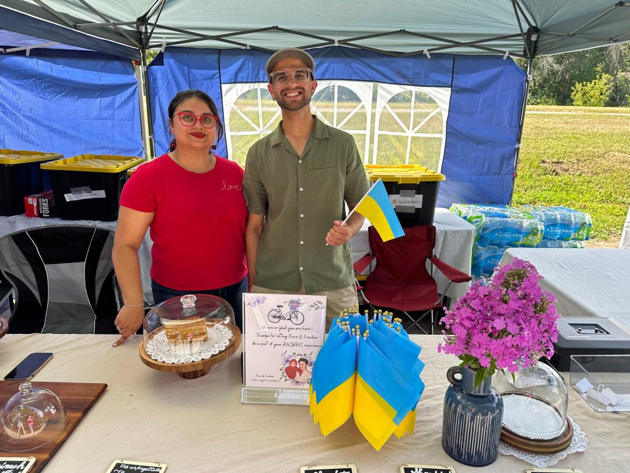 Shalika Khindurangala and her brother Lalit Khindurangala pose with Ukrainian flags and honey cake at Brookside Park Tuesday morning. Their bakery business, Piece & Freedom, was ready to serve RAGBRAI riders menu items that feature the flavors of Ukraine.