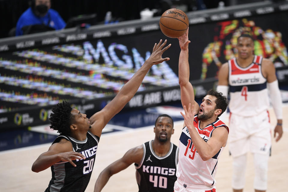 Washington Wizards guard Raul Neto (19) shoots against Sacramento Kings center Hassan Whiteside (20) and forward Harrison Barnes (40) during the first half of an NBA basketball game, Wednesday, March 17, 2021, in Washington. (AP Photo/Nick Wass)