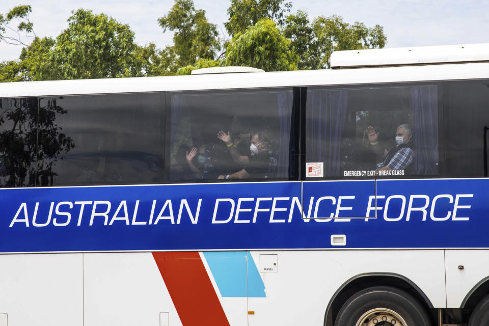 Evacuees wear masks and wave as they are bussed to a quarantine facility after arriving in Darwin, Australia, Thursday, Feb. 20, 2020. The evacuees have travelled from Japan after being stranded on the cruise ship Diamond Princess. (Helen Orr/AAP Image via AP)