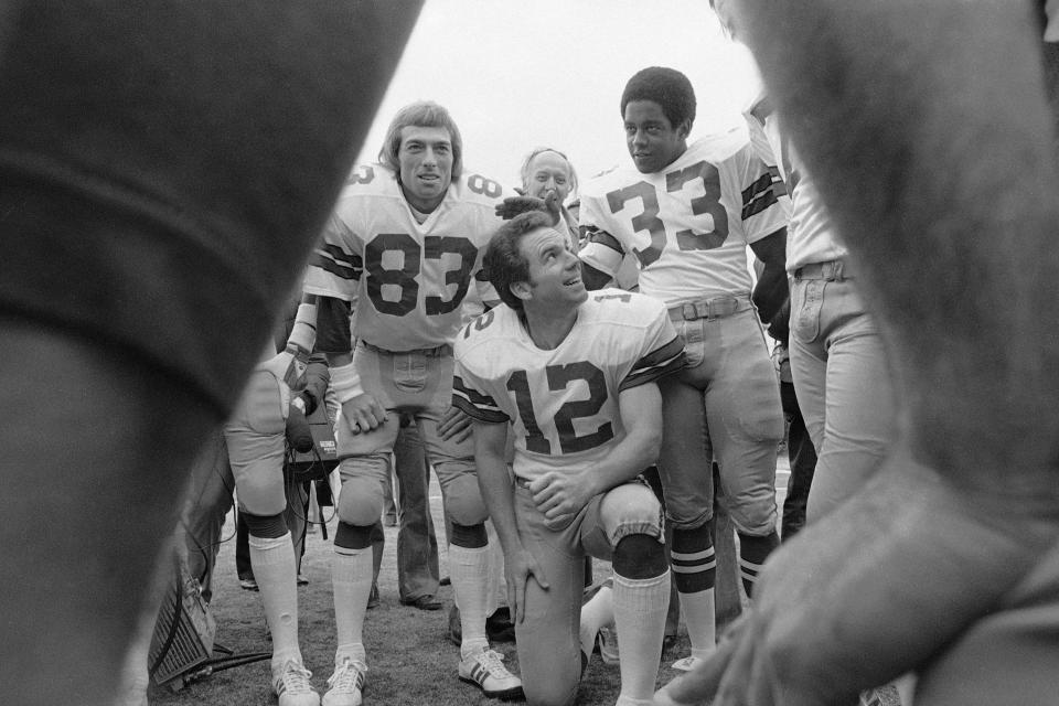 Dallas Cowboys Roger Staubach smiles up at Tony Dorsett during photo session, Jan. 11, 1978 for Super Bowl XII. Golden Richards (83) completes the picture. | Associated Press