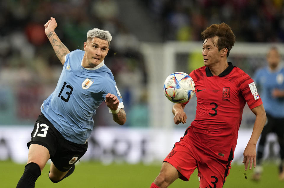 Uruguay's Guillermo Varela, left, duels for the ball with South Korea's Kim Jin-su during the World Cup group H soccer match between Uruguay and South Korea, at the Education City Stadium in Al Rayyan , Qatar, Thursday, Nov. 24, 2022. (AP Photo/Lee Jin-man)