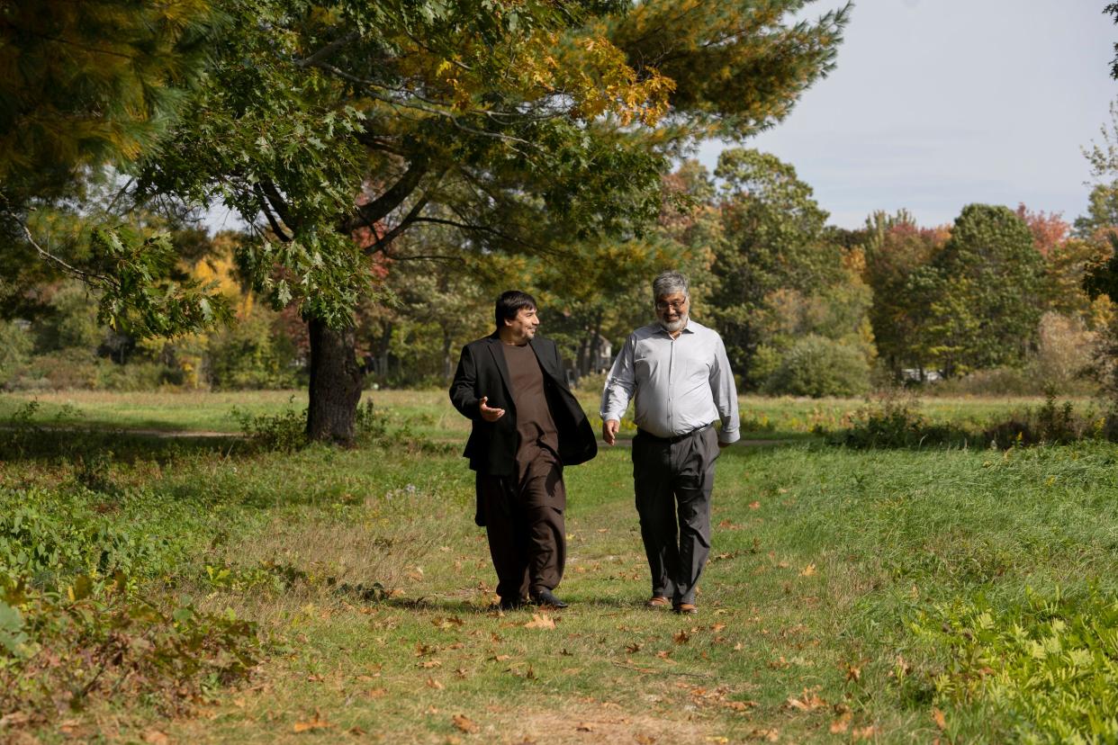 Two men are seen walking along a path through a field.