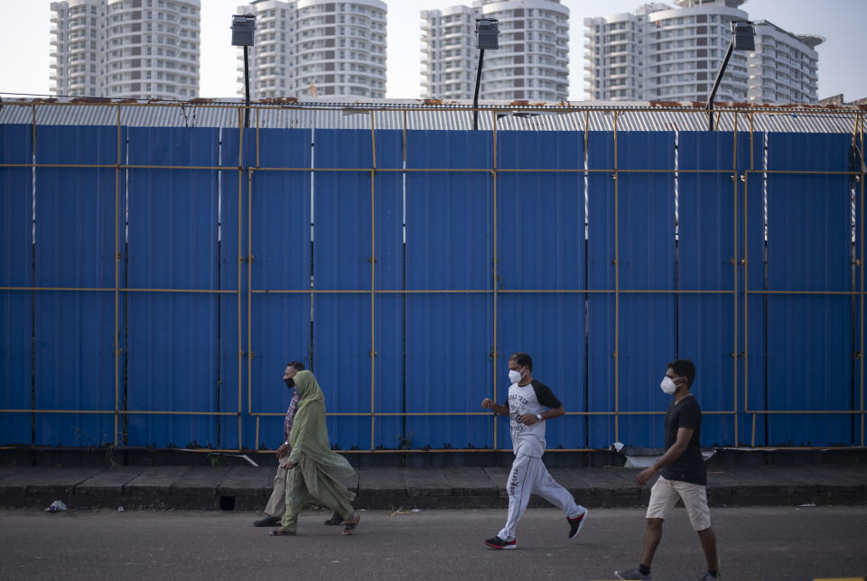 People wearing masks as a precaution against the coronavirus take a morning walk past a high-rise residential complex in Kochi, Kerala state, India, Friday, Nov. 20, 2020. India's total number of coronavirus cases since the pandemic began crossed 9 million on Friday. (AP Photo/R S Iyer)