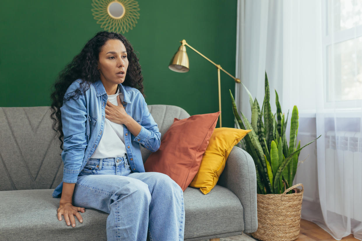 Woman having trouble breathing sitting on a sofa