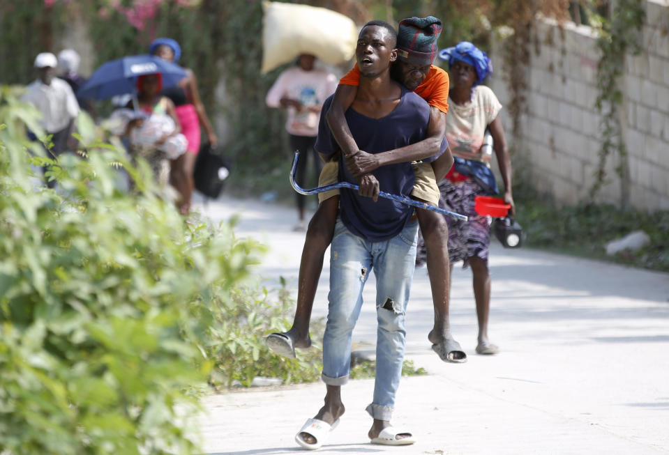 Un residente carga a una persona mayor a la espalda mientras huyen de su casa para evitar los enfrentamientos entre bandas armadas en el distrito de Pernier de Petion-Ville, Haití, el 31 de enero de 2024. (AP Foto/Odelyn Joseph)