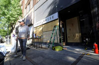 Owner Johnny Grimes stands outside his salon Monday, June 1, 2020, in Birmingham, Ala., as he works to board up the windows after it was vandalized and looted. Grimes said he was devastated by what had happened to his business but was sympathetic with those who demonstrated against police brutality. (AP Photo/Jay Reeves)