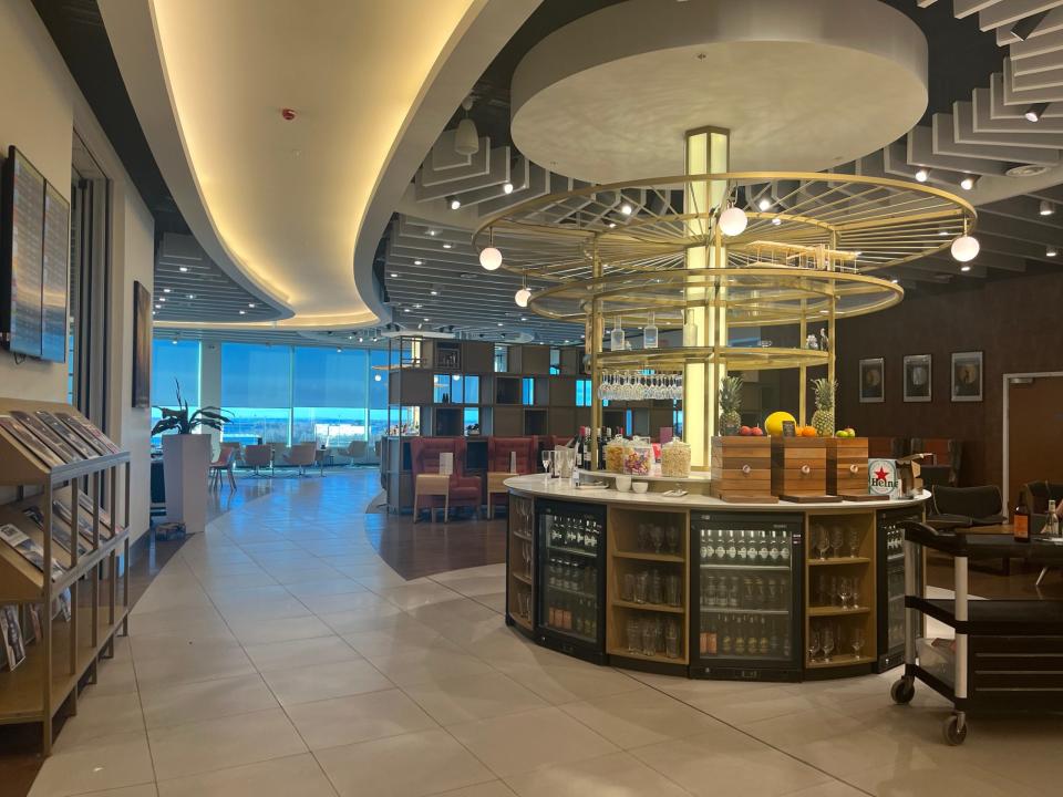 Virgin Atlantic lounge with a circular bar area, red seating, and a long hallway leading into a larger dining area - Copyright: Emma Kershaw