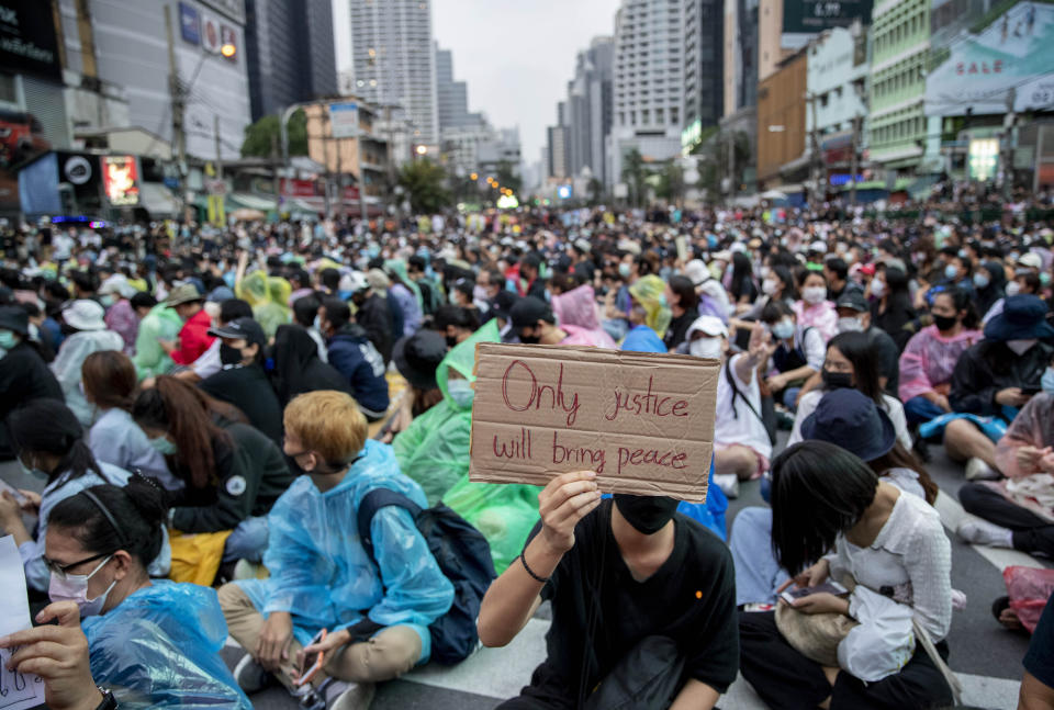 A supporter of pro-democracy movement displays a placard during a protest rally at an intersection in Bangkok, Thailand, Sunday, Oct. 18, 2020. Pro-democracy activists in Thailand launched their fifth straight days of protests on Sunday, scheduling demonstrations not just in the capital but also at several other locations around the country. (AP Photo/Gemunu Amarasinghe)