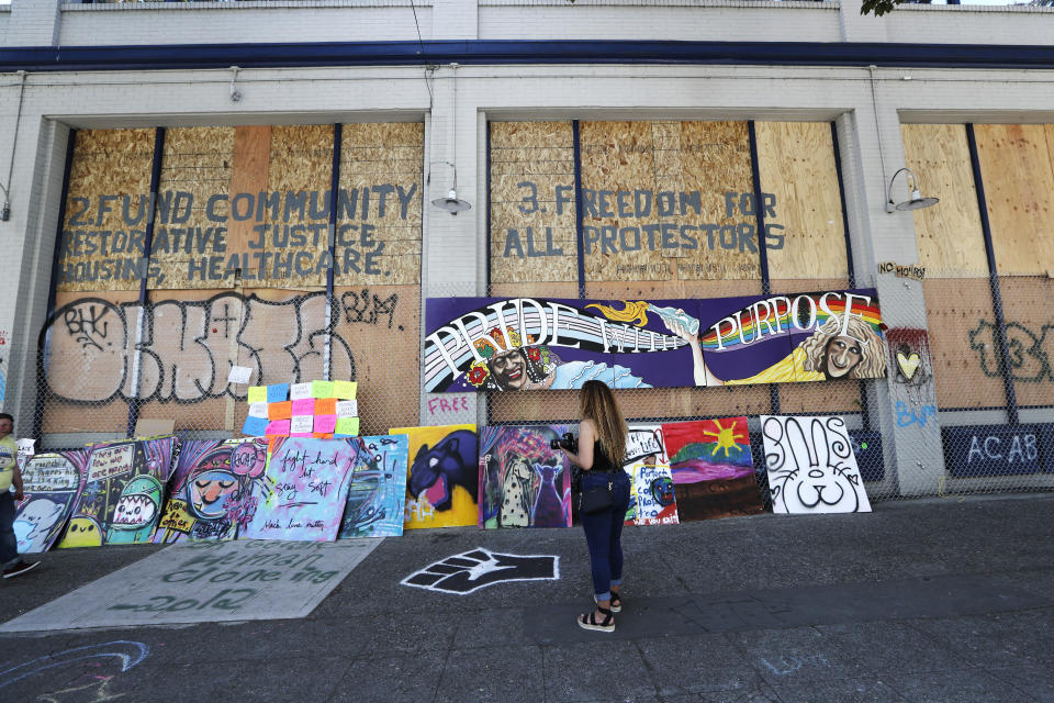 Plywood and artwork cover a wall on a closed police precinct Thursday, June 18, 2020, in Seattle, in what has been named the Capitol Hill Occupied Protest zone. Police pulled back from several blocks of the city's Capitol Hill neighborhood near the police department's East Precinct building earlier in the month after clashes with people protesting the death of George Floyd in Minneapolis. (AP Photo/Elaine Thompson)
