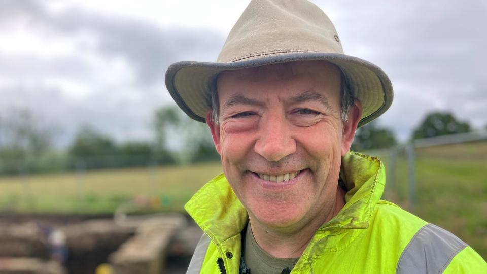 A smiling man in a fluorescent jacket and hat.