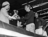 <p>Queen Elizabeth II presents the Jules Rimet trophy to the captain of the British team following England's world title win at the World Cup in Wembley. </p>