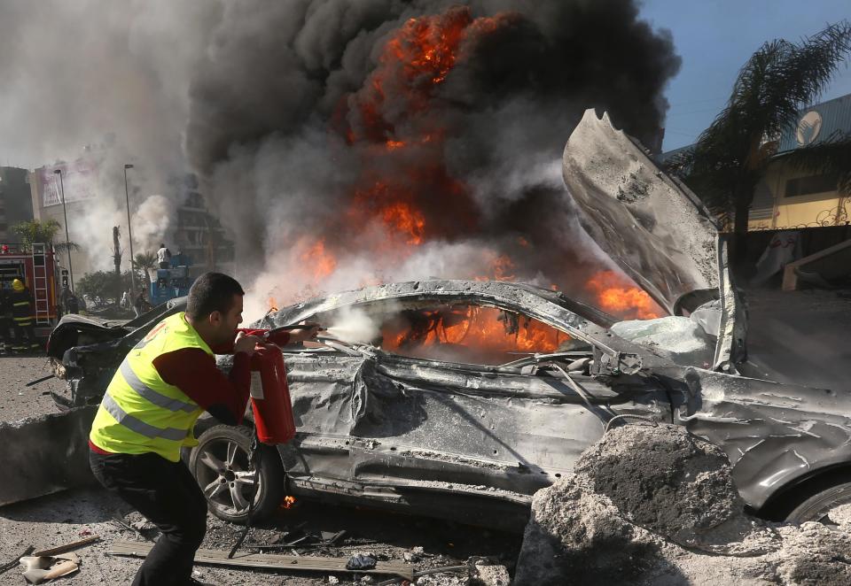 A Lebanese firefighter extinguishes a burned car at the site of an explosion, near the Kuwaiti Embassy and Iran's cultural center, in the suburb of Beir Hassan, Beirut, Lebanon, Wednesday, Feb. 19, 2014. A blast in a Shiite district in southern Beirut killed several people on Wednesday, security officials said — the latest apparent attack linked to the civil war in neighboring Syria that has killed and wounded scores of people over the last few months. (AP Photo/Hussein Malla)