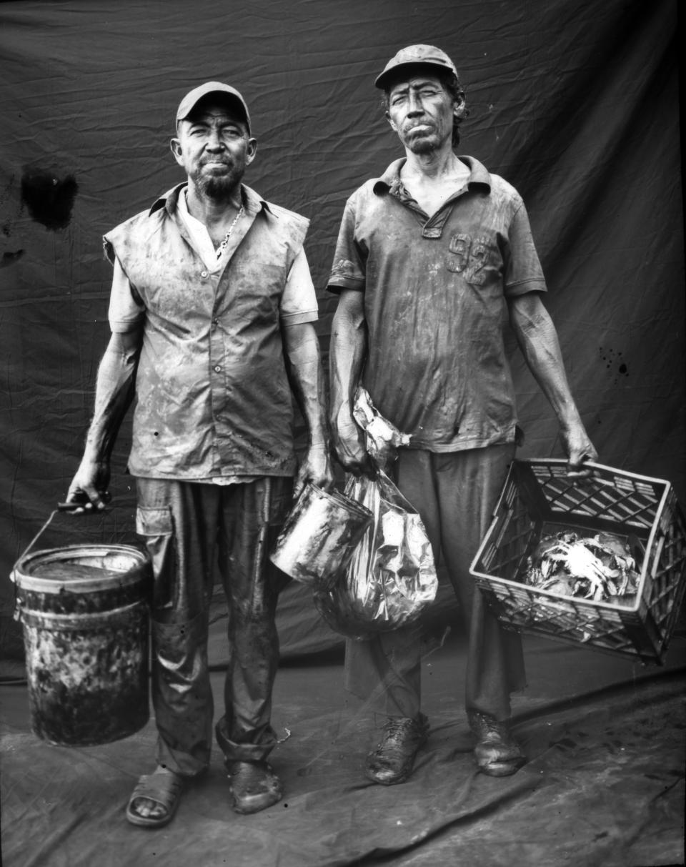 Fisherman Antonio Tello, left, poses for a portrait with his brother after harvesting crabs in oil-contaminated Lake Maracaibo in Cabimas, Venezuela. (Photo: Rodrigo Abd/AP)