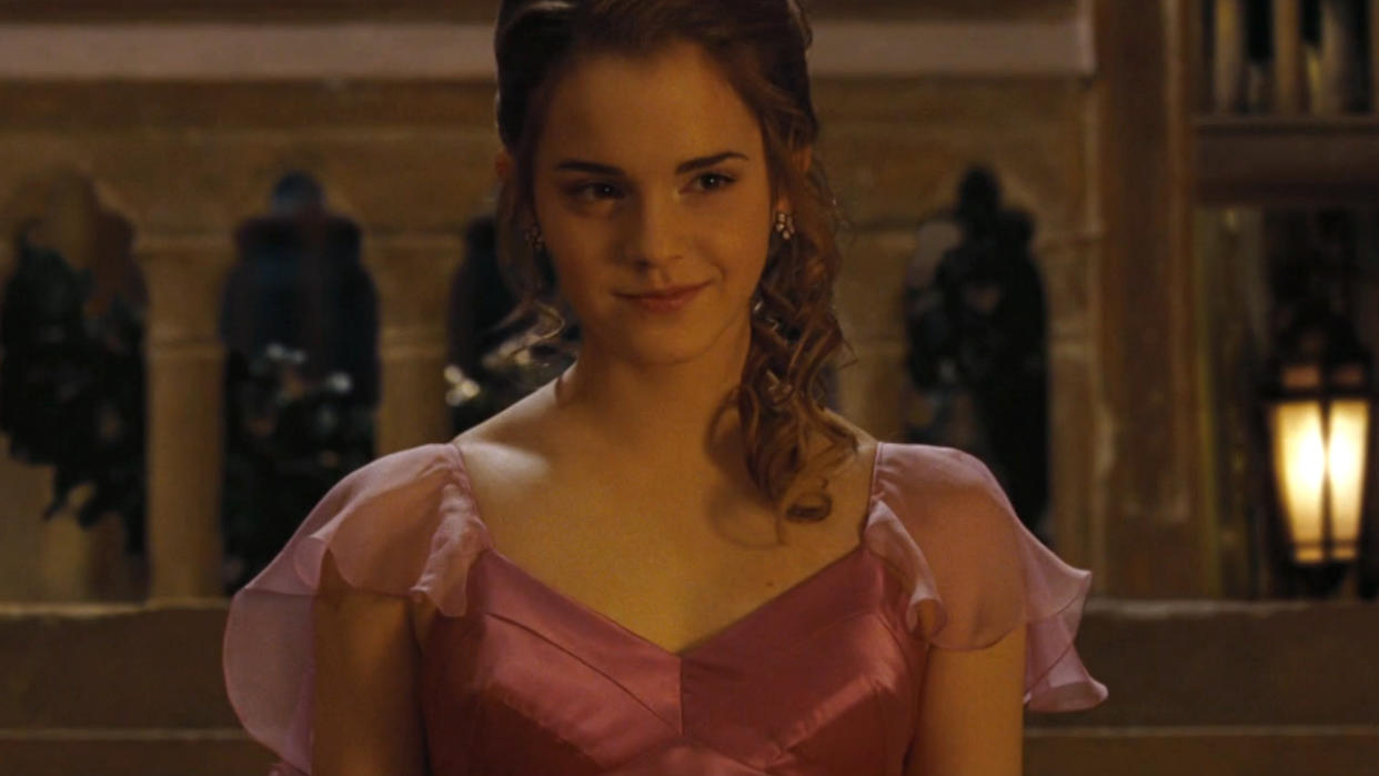  Emma Watson smiling in a pink dress as she walks down the stairs in Harry Potter and the Goblet of Fire. 