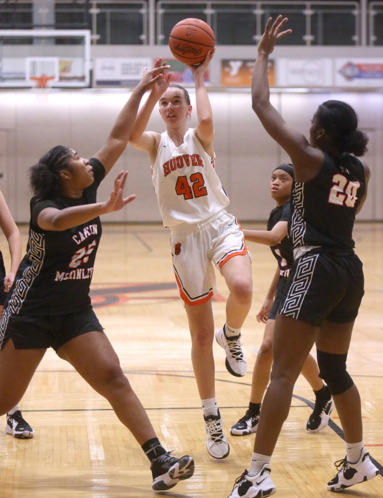 Janet Eriksen, 42, of Hoover goes to the basket while being defended by X'Zariya Fannin, left, and Ariahna Snell, right, of McKinley during their game at Hoover on Dec. 1.