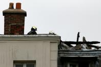 Firefighters assess damages on the roof of a future migrant center after an alleged arson attack that occured overnight on September 6, 2016 in Forges-les-Bains, some 50 kilometers southwest of Paris