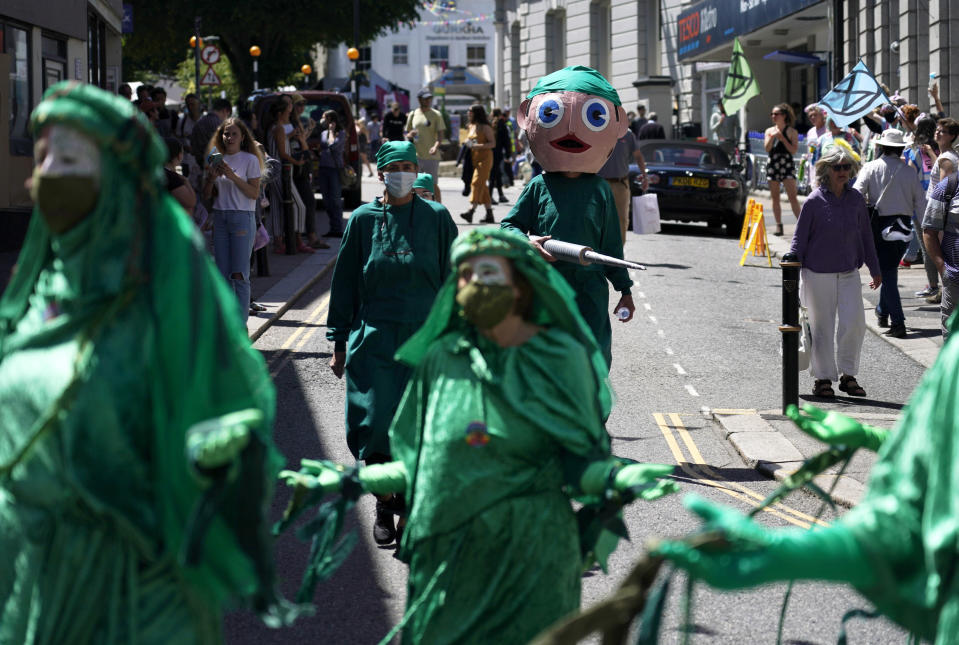 Climate activists and others hold signs and banners as they march in costume through the streets during a demonstration around the meeting of the G7 in Falmouth, Cornwall, England, Saturday, June 12, 2021. Leaders of the G7 gather for a second day of meetings on Saturday, in which they will discuss COVID-19, climate, foreign policy and the economy. (AP Photo/Alberto Pezzali)