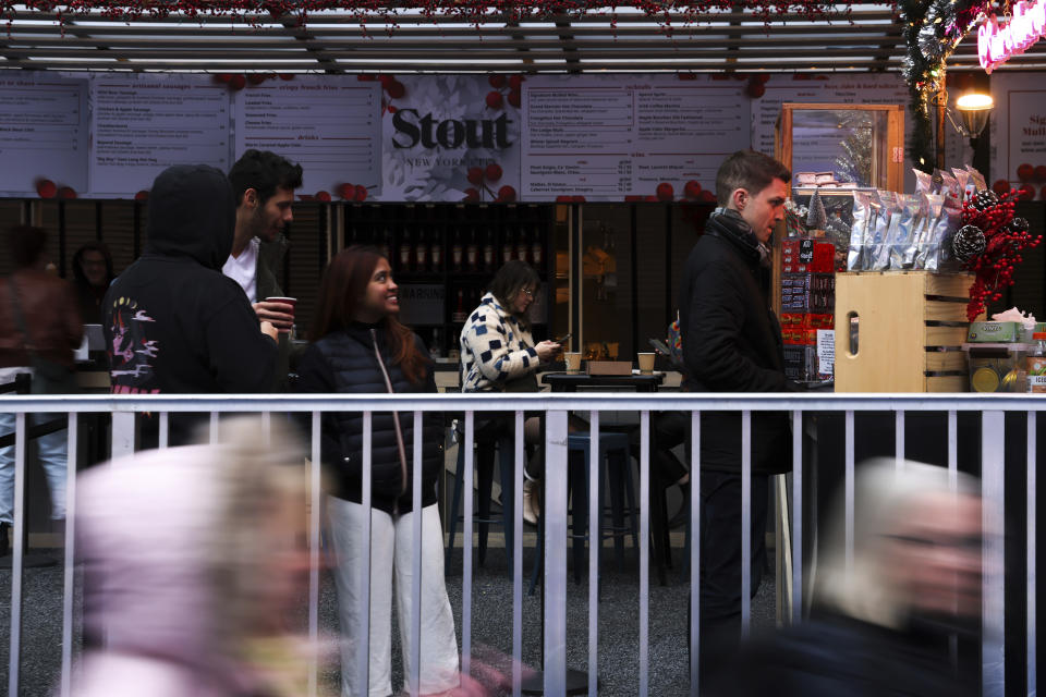 People wait in line at a shop in Bryant Park's Winter Village, Tuesday, Nov. 15, 2022, in New York. After two years of pandemic holidays when people spent more dollars online, shoppers are back in force in stores and at holiday markets. Small businesses say it is beginning to feel a lot like Christmas, both emotionally and financially. (AP Photo/Julia Nikhinson)