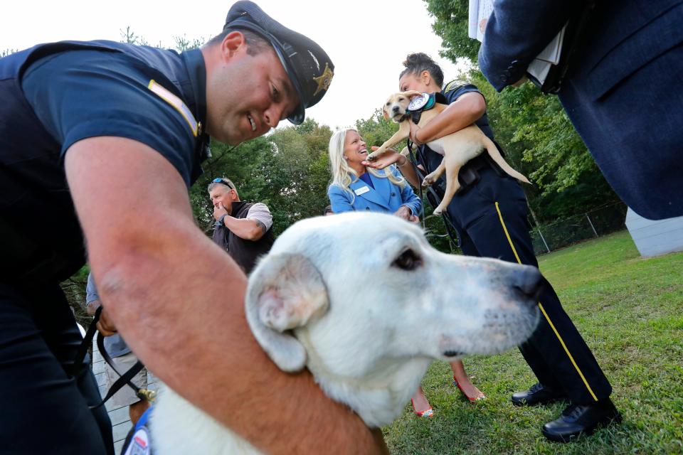 Officer Chris Vaz meets his new comfort dog Jack for the first time while in the background Jill Fearons, President of Friends of Jack, speaks with officer Shanna Sears-Oatley holding her new dog Hero at a press conference announcing two comfort dog donations by the Friends of Jack Foundation to the Bristol County House of Correction in Dartmouth.