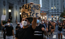 FILE - This photo from Thursday July 30, 2020, shows a demonstrator holding a sign that reads "Defund the police" during a protest march in New York. The chaos unleashed in 2020, amid the coronavirus pandemic, has created space for different voices to speak, for different conversations to be had and for different questions to be asked. (AP Photo/John Minchillo, File)