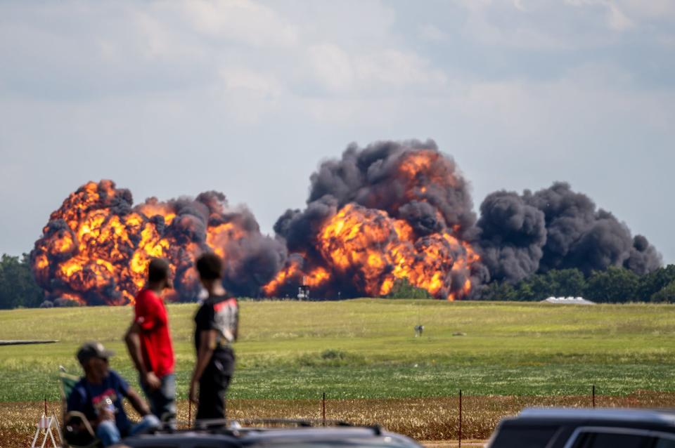 Spectators look on after a MiG-23 aircraft crashed into the ground at the Thunder over Michigan air show at the Willow Run Airport in Ypsilanti on Sunday, Aug. 13, 2023. Two people reportedly ejected from the aircraft prior to the crash.