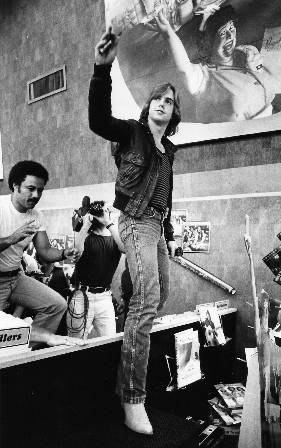 Shaun Cassidy waves to young fans while climbing over a record rack at Grapevine Records & Tapes on Aug. 28, 1979, at Westgate Plaza in Akron.