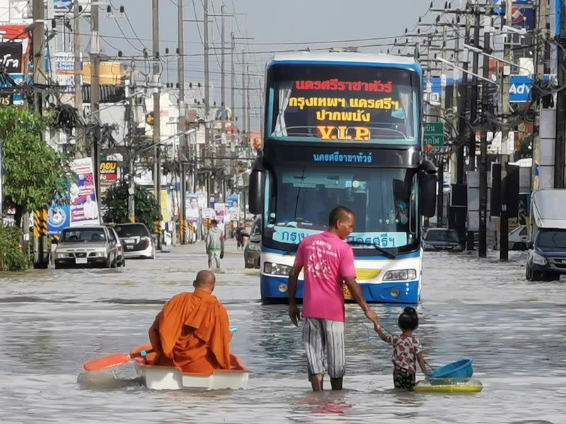 Buddhist monk paddles a boat down a flooded street in Nakon Si Thammarat province