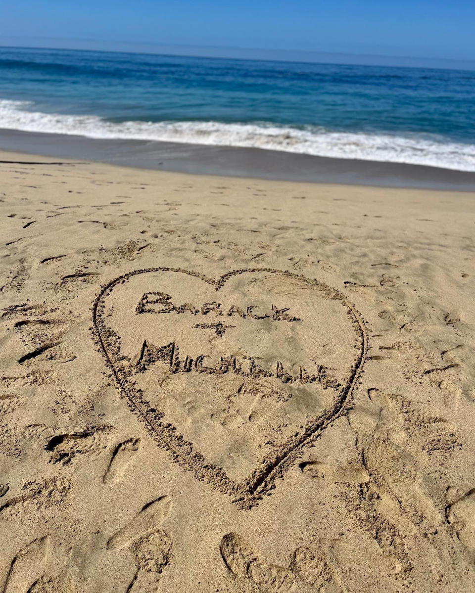 Barack and Michelle names are written in the sand with the shape of a heart around them. (@barackobama via Instagram)