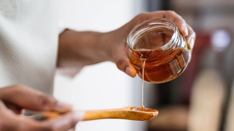 Person pouring syrup into wooden spoon