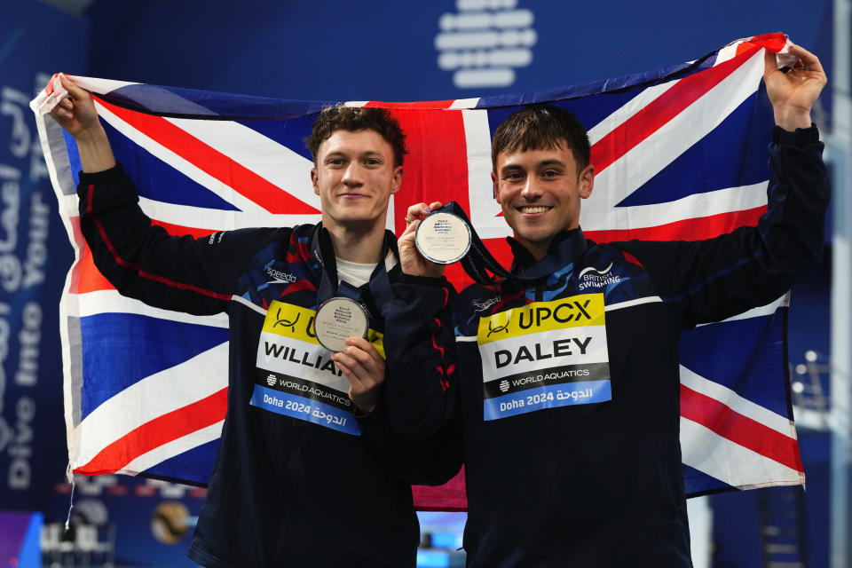 Thomas Daley and Noah Williams of Great Britain hold up their silver medals and the Union Jack during the Men's synchronized 10m platform diving final at the World Aquatics Championships in Doha, Qatar, Thursday, Feb. 8, 2024. (AP Photo/Hassan Ammar)