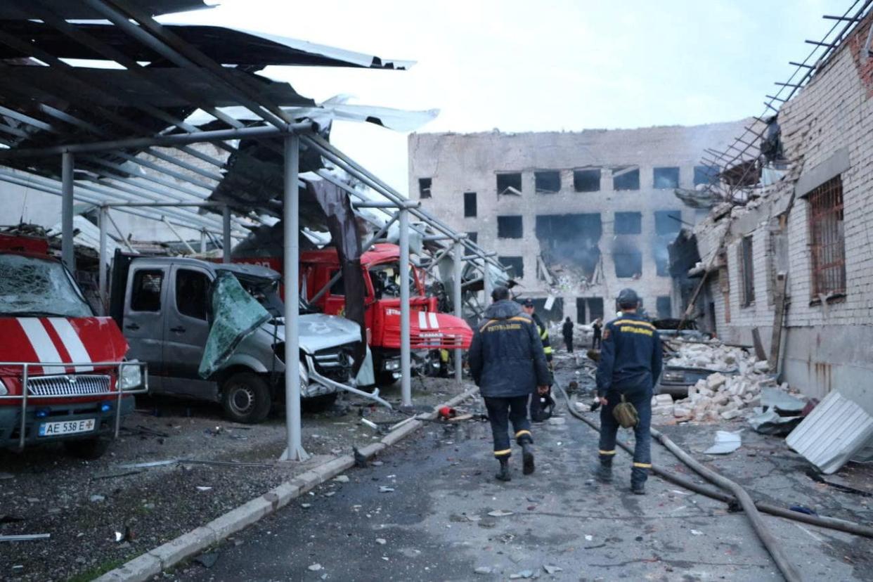 Rescuers walk along of destroyed vehicles at a compound of a fire depot of the State Emergency Service heavily damaged by a Russian missile strike (via REUTERS)