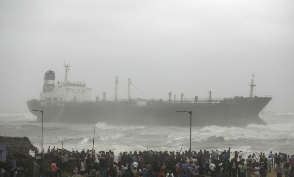 People look at Indian ship Pratibha Cauvery that ran aground with people on board, reportedly due to strong winds on the Bay of Bengal coast in Chennai, India, Wednesday, Oct. 31, 2012. More than 100,000 people were evacuated from their homes Wednesday as a tropical storm hit southern India from the Bay of Bengal, officials said.Rain lashed the region and strong winds uprooted trees in some places. Weather officials said the storm packed winds of up to 100 kilometers (60 miles) per hour as it made landfall near Chennai, the capital of Tamil Nadu state. (AP Photo/Arun Sankar K)