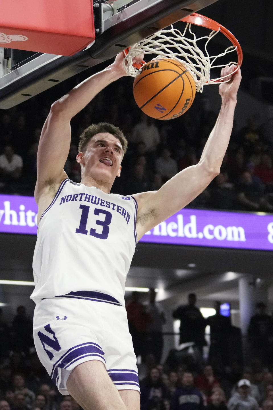 Northwestern guard Brooks Barnhizer hangs from the rim after dunking during the second half of an NCAA college basketball game against Nebraska in Evanston, Ill., Wednesday, Feb. 7, 2024. Northwestern won 80-68. (AP Photo/Nam Y. Huh)