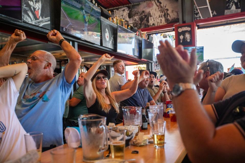 People raise their arms and cheer at a table.