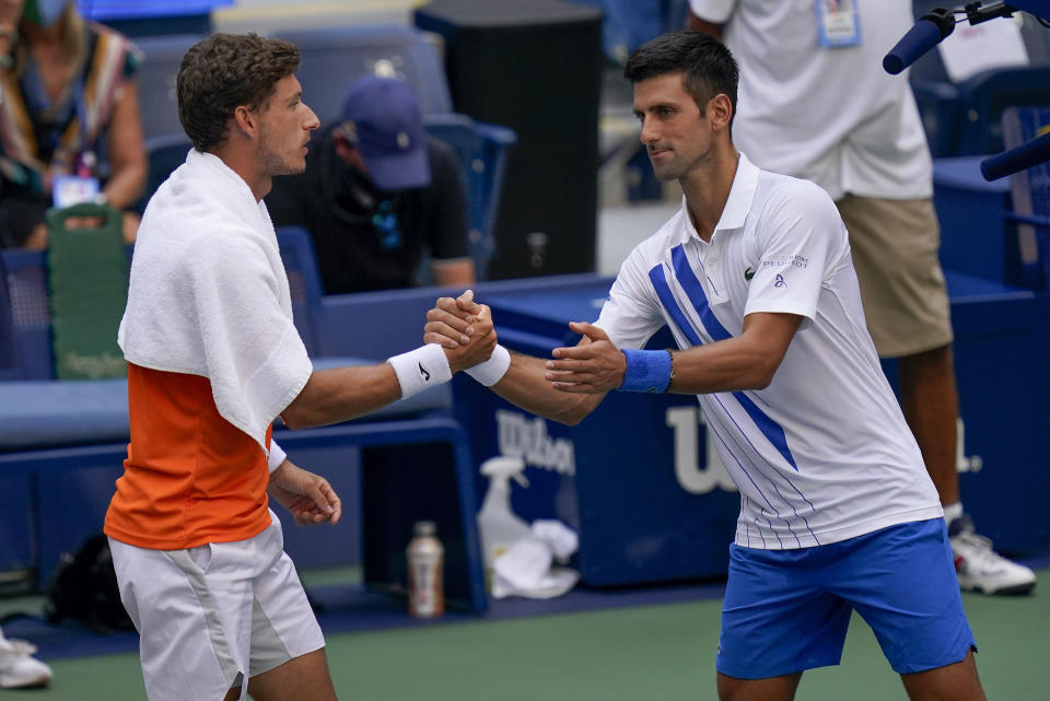 Novak Djokovic (derecha) saluda a Pablo Carreño Busta tras ser descalificado por propinarle un pelotazo a la jueza de línea durante el partido de octavos de final del Abierto de Estados Unidos, el domingo 6 de septiembre de 2020, en Nueva York. Djokovic fue descalificado. (AP Foto/Seth Wenig)